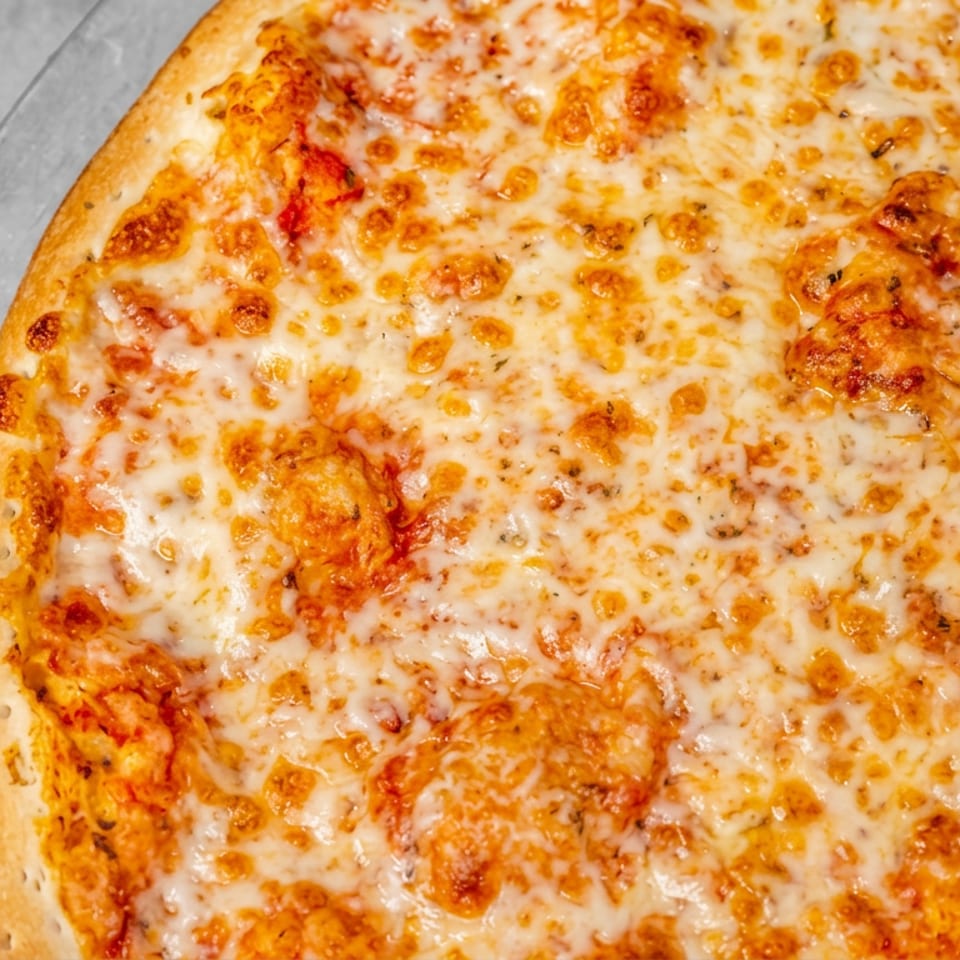 Close-up of a golden cheese pizza with browned melted cheese and visible toppings on a metal tray.